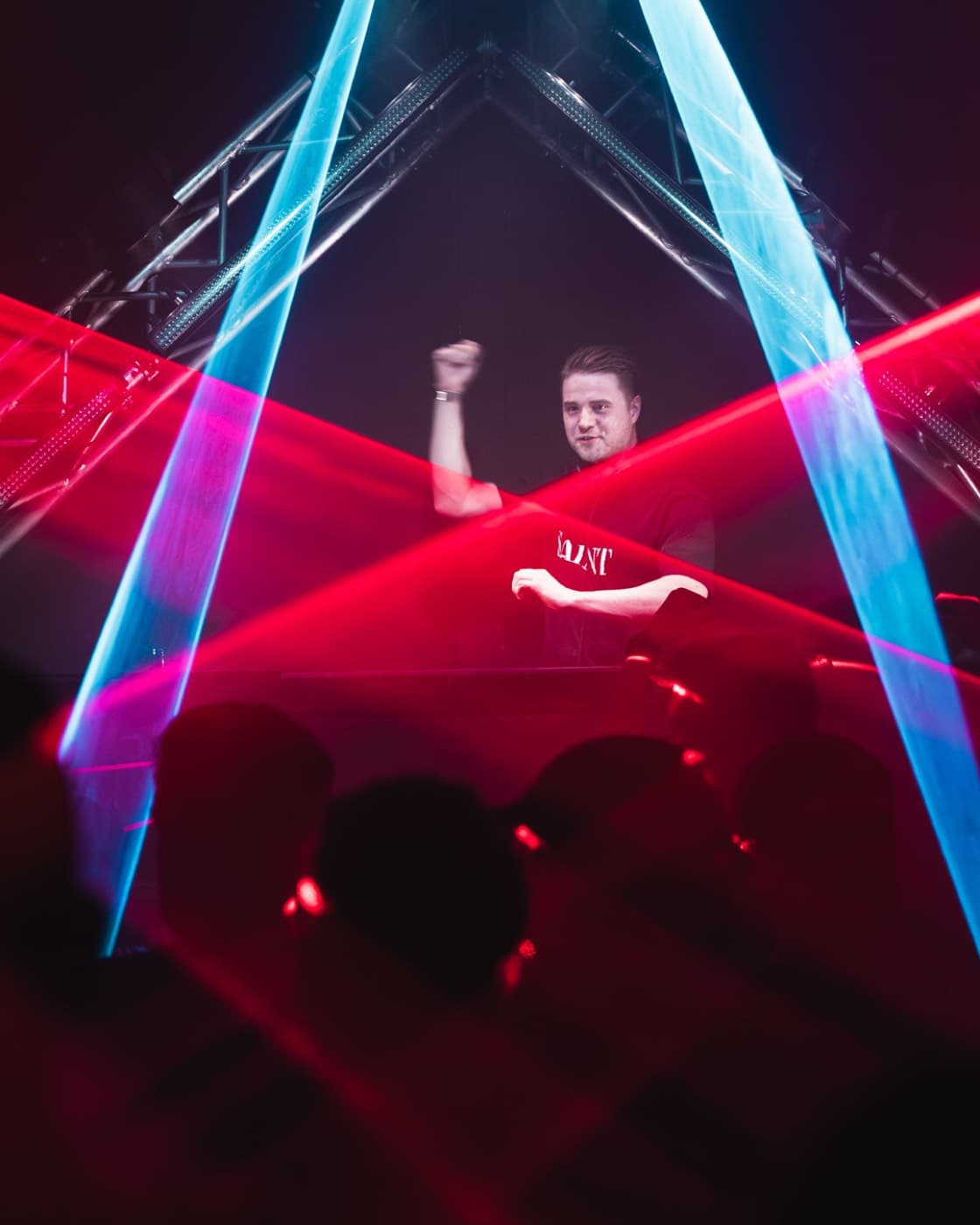DJ mit erhobener Faust unter kreuzenden roten und blauen Laserstrahlen