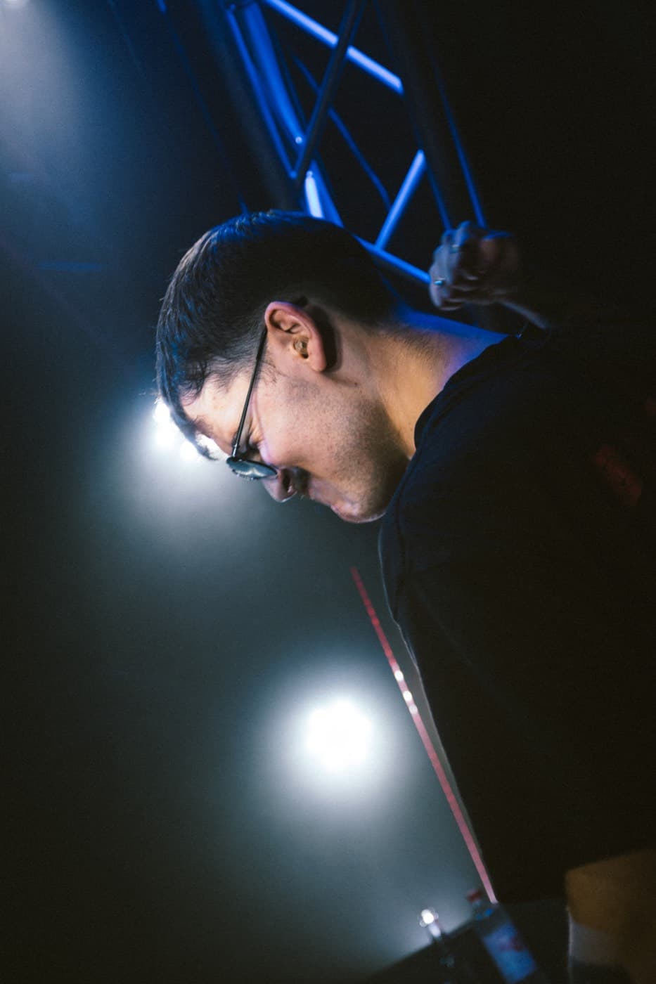 Seitenporträt eines DJ im blauen Bühnengegenlicht, konzentriert nach unten blickend